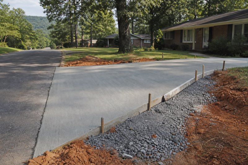 Continuous extruded concrete landscape curbing separating a green lawn from a mulched planting bed at an Alabama home